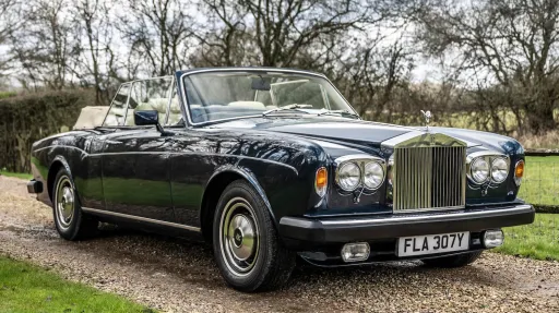 Right front view of blue Rolls-Royce corniche with twin headlights and soft top roof open