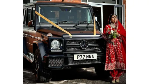 Asian bride standing beside a black Mercedes G-Wagon decorated with wedding ribbons