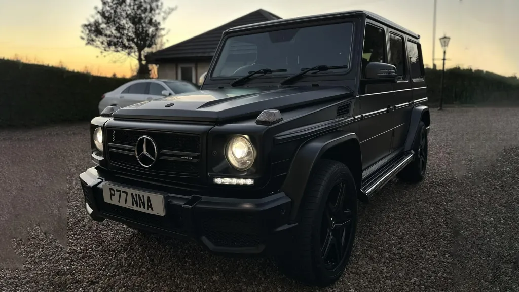 Black Mercedes G-Wagon photographed at sunset with headlights on