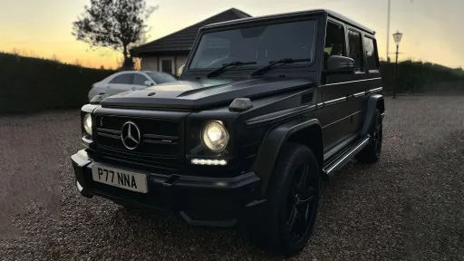 Black Mercedes G-Wagon photographed at sunset with headlights on