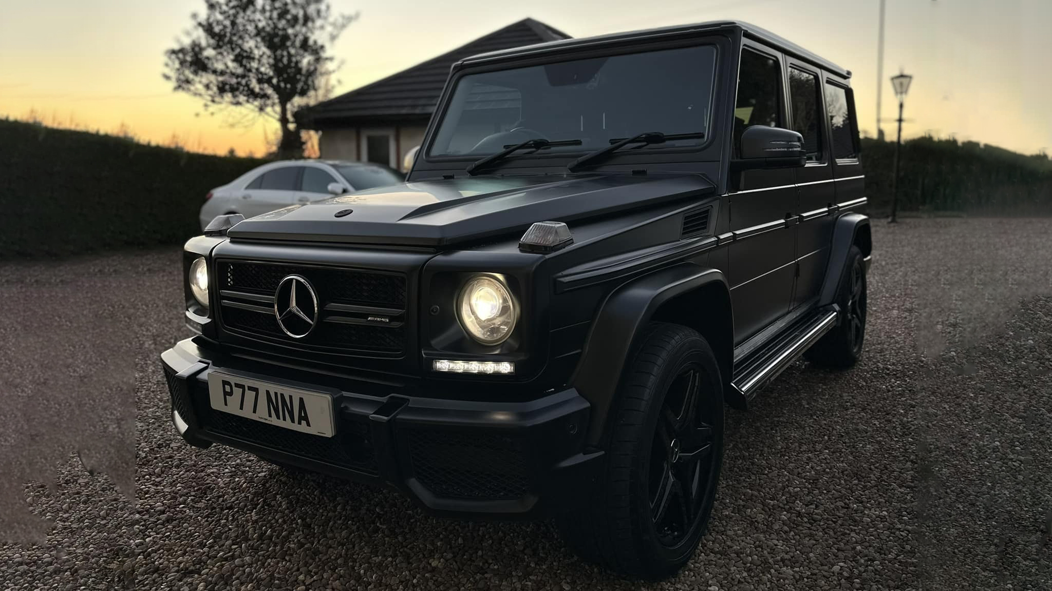 Black Mercedes G-Wagon photographed at sunset with headlights on