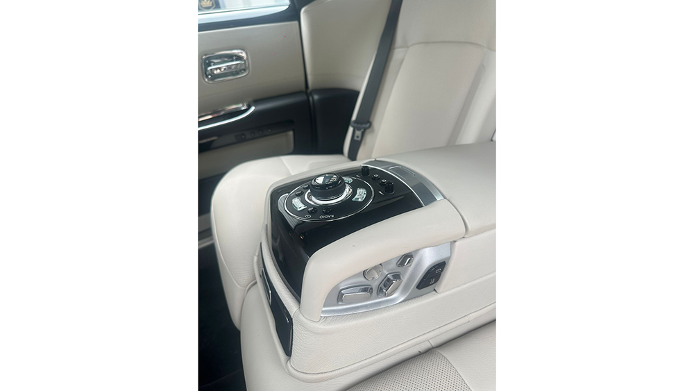 Close-up of the Rolls-Royce Phantom’s cream leather rear interior showing the centre console and armrest inside the luxury cabin.