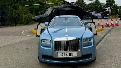 Detailed front view of the Rolls-Royce Ghost’s chrome grille and Spirit of Ecstasy, with the light blue bonnet reflecting the sky.