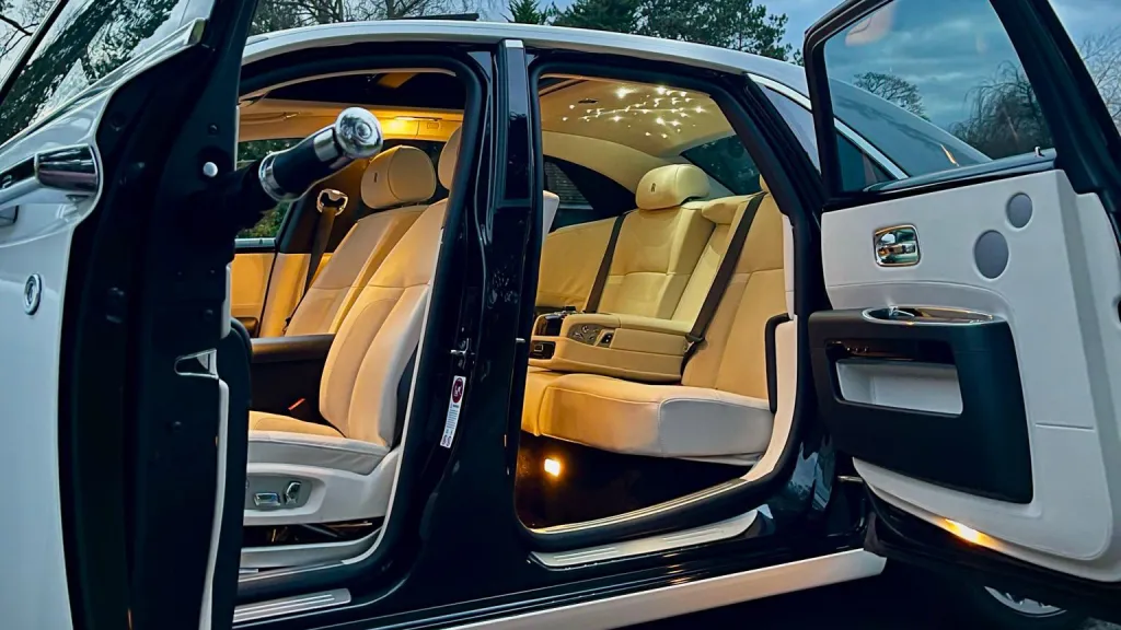 Close-up of the Ghost’s rear cabin with tan leather seating and warm ambient lighting, viewed through the open rear-hinged door.