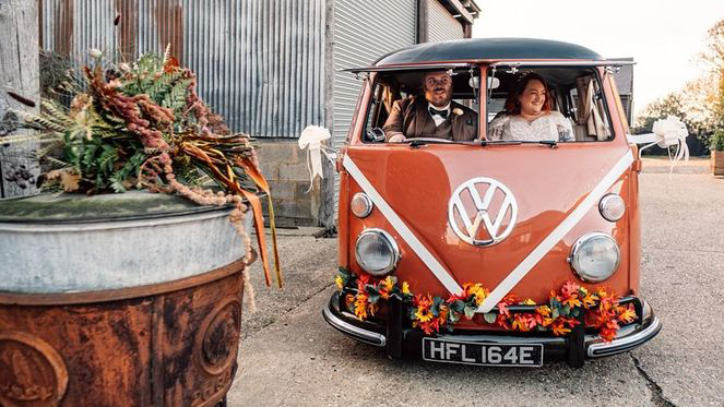 Full front view of a classic Volkswagen Splitscreen Campervan decorated with Autumn coloured leaves and flowers