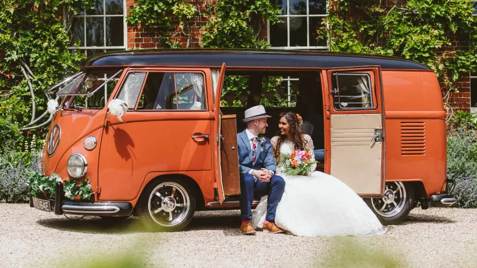 Bride and groom sitting on the rear step of a Classic VW Campervan