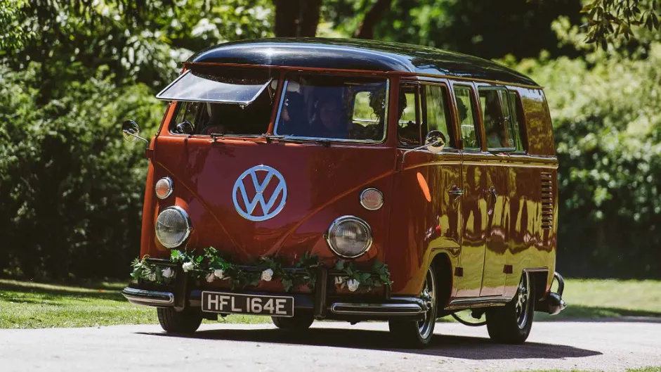 Left side view of Volkswagen Splitscreen Campervan driving in to a wedding venue