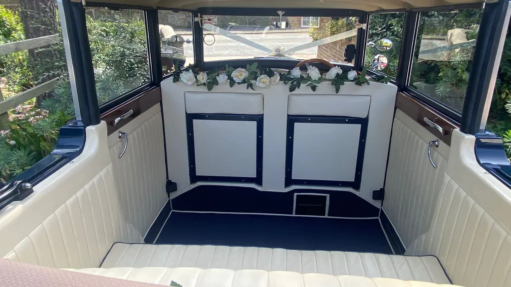 View of the Regent wedding car’s cream-coloured interior with blue carpet, floral decorations and classic wood trim.