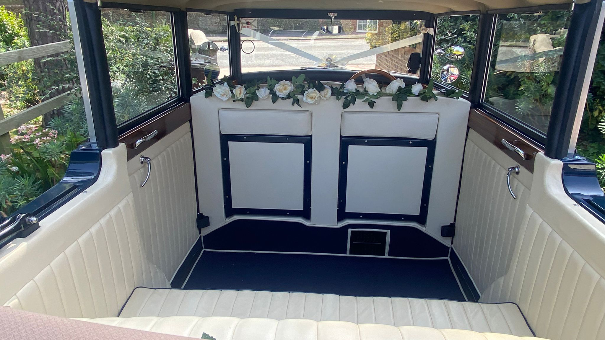 View of the Regent wedding car’s cream-coloured interior with blue carpet, floral decorations and classic wood trim.