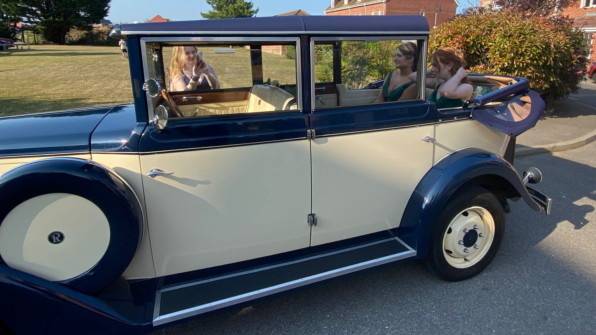 Another full left-side angle of the cream and blue Regent wedding car on a quiet residential street with rear semi-convertible roof open