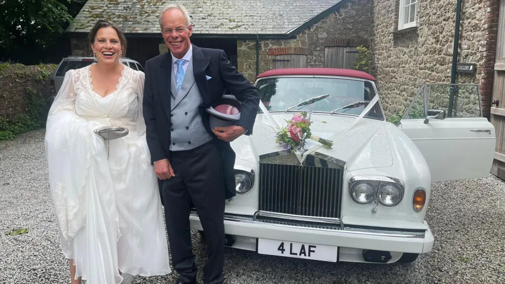Couple standing in front of a classic White rolls-Royce at a Devon venue