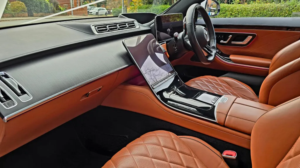 Front interior of a Mercedes S-Class 500 showing tan quilted leather seats, modern dashboard and digital displays.
