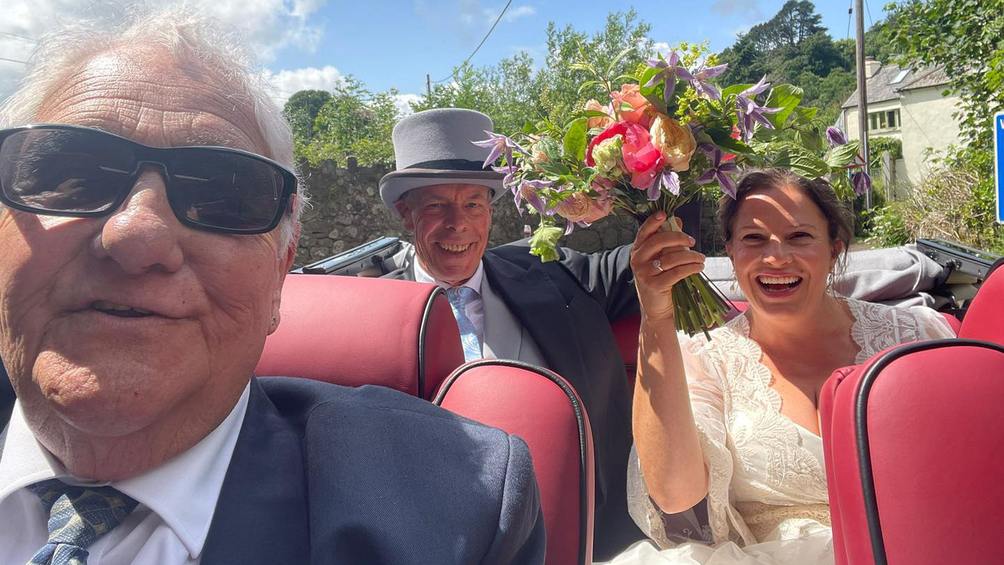 Selfie of happy couple with their chauffeur smiling.