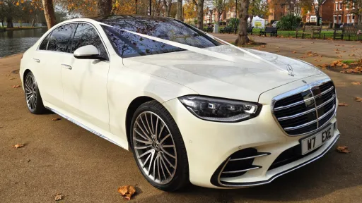 White Mercedes S-Class 500 decorated with white wedding ribbons on the bonnet.