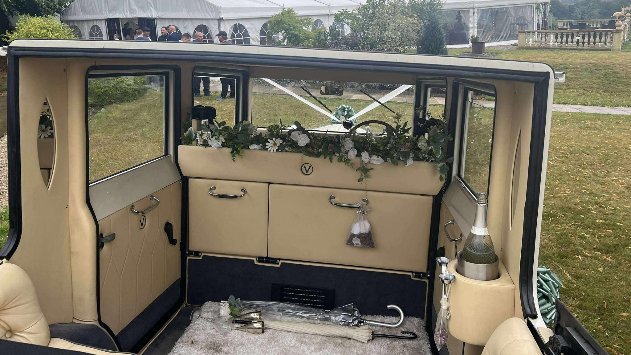 Inside rear seating area of the Viscount wedding car showing cream upholstery, polished wood trim and decorative features, with the soft-top roof open to natural light.