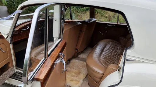 Interior view of the Rolls Royce Silver Cloud Mk I featuring tan leather seats, polished wooden trim and spacious rear passenger seating.