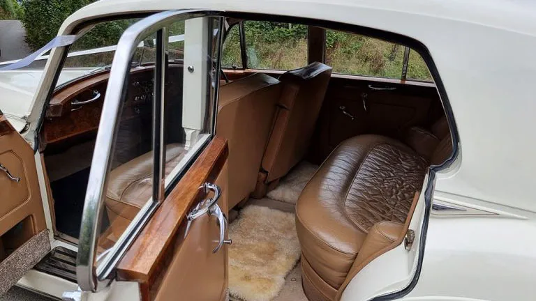 Interior view of the Rolls Royce Silver Cloud Mk I featuring tan leather seats, polished wooden trim and spacious rear passenger seating.