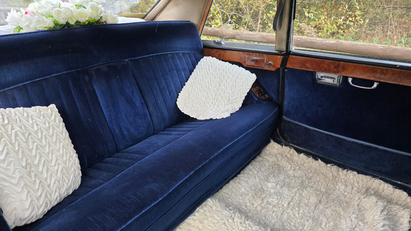 Rear view of the classic Daimler's blue velour seating with wooden trim and cream cushions.