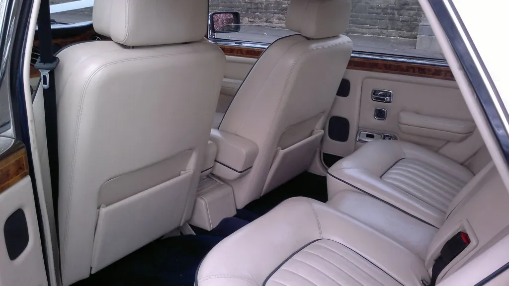 Cream leather interior of a Rolls-Royce Silver Spirit showing rear seating, wooden trim and spacious legroom.
