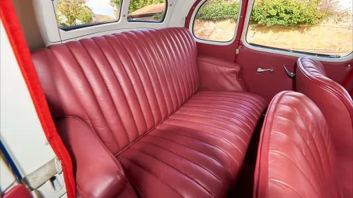 Close-up of the burgundy leather rear seats inside a 1937 Austin 10 Cambridge, showcasing its restored vintage upholstery and spacious period interior.
