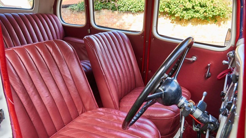 Front interior view of the 1937 Austin 10 Cambridge wedding car, highlighting the burgundy leather seats, original steering wheel and classic dashboard details.
