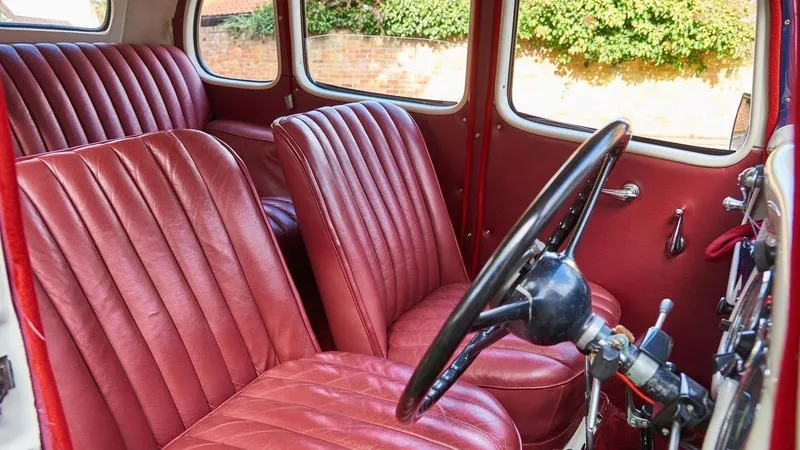 Front interior view of the 1937 Austin 10 Cambridge wedding car, highlighting the burgundy leather seats, original steering wheel and classic dashboard details.