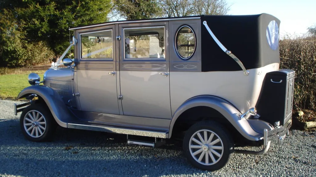 Rear left side view of silver imperial wedding car with white ribbons and bows