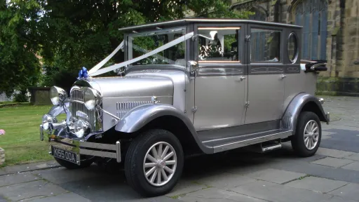 Silver imperial wedding car dressed with white ribbons and a blue bow