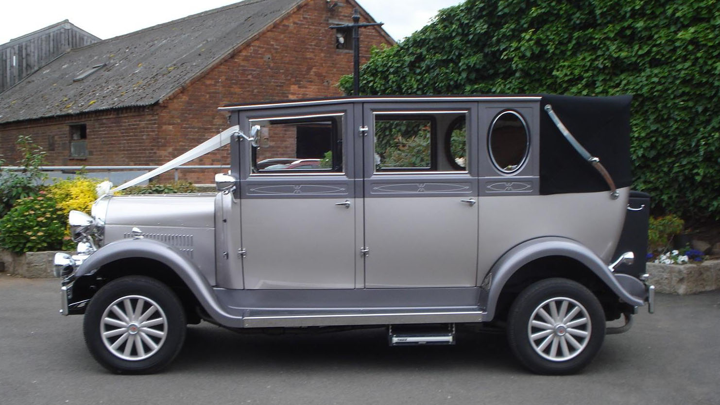 left side view silver mperial wedding car with grey soft top roof closed