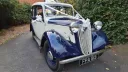 Blue and ivory 1937 Austin 10 Cambridge parked on a quiet road, highlighting the classic chrome grille and vintage charm suitable for Leicester weddings.
