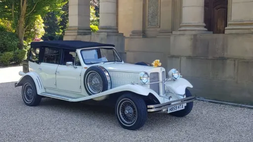 Old English White Beauford 4-door convertible wedding car outside a historic building in Bradford