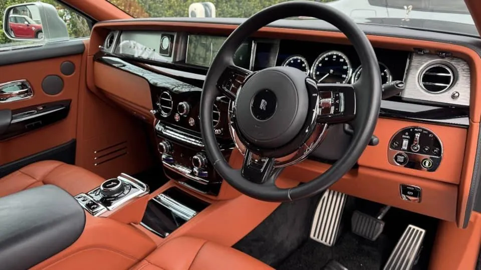 Front dashboard and steering wheel of black and silver Rolls-Royce Phantom VIII interior