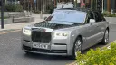 Black and silver Rolls-Royce Phantom VIII at dusk with headlights illuminated