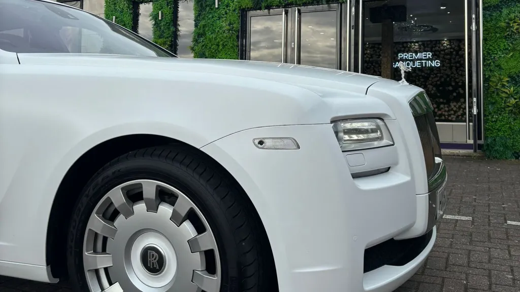Front view of a white Rolls-Royce Ghost wedding car showing signature grille and Spirit of Ecstasy at an urban wedding location