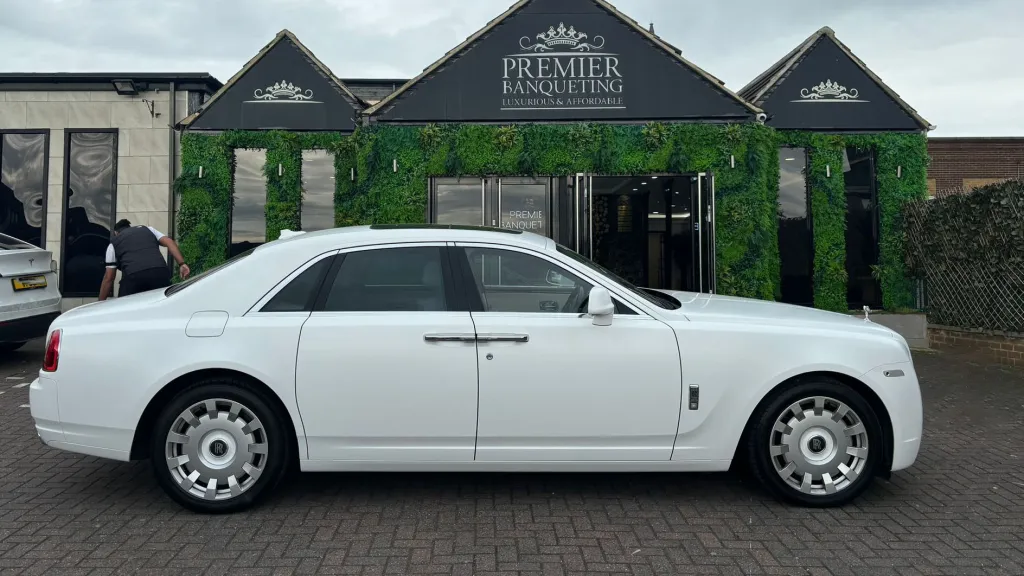 Side view of a white Rolls-Royce Ghost wedding car parked outside Asian Premier Banqueting Hall, ideal for luxury weddings