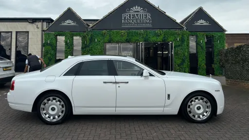 Side view of a white Rolls-Royce Ghost wedding car parked outside Asian Premier Banqueting Hall, ideal for luxury weddings