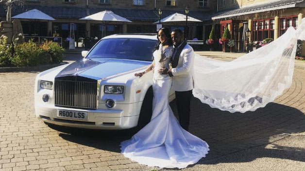 Bride and groom posing beside a white Rolls-Royce Phantom wedding car with the bride’s veil flowing, photographed outdoors in West Yorkshire