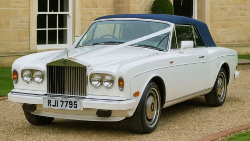 Classic white Rolls-Royce Corniche convertible wedding car parked outside a stone venue in Yorkshire with roof closed