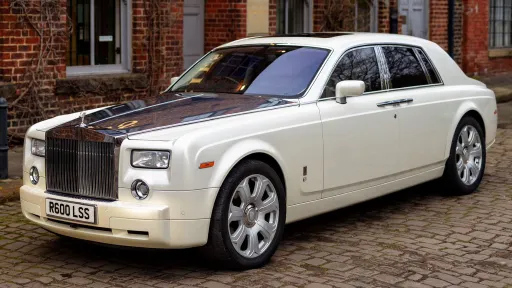 White Rolls-Royce Phantom wedding car parked on cobblestones outside a traditional brick venue in Bradford
