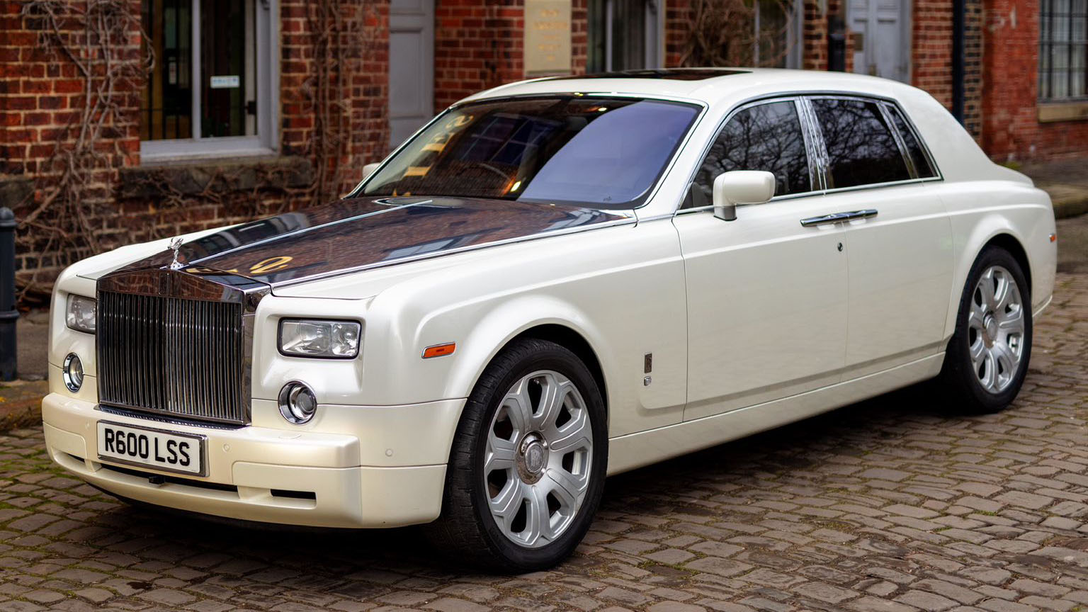 White Rolls-Royce Phantom wedding car parked on cobblestones outside a traditional brick venue in Bradford