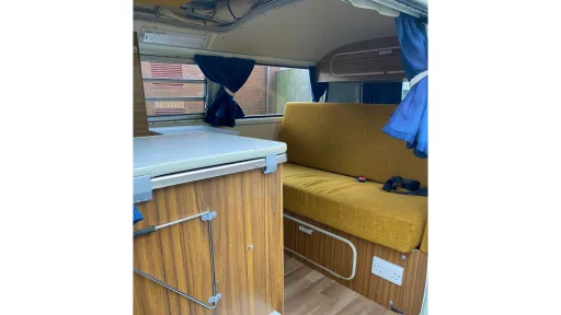 Interior of a blue Bay Window VW Campervan Westfalia showing original Westfalia cabinetry, seating and light-filled cabin.