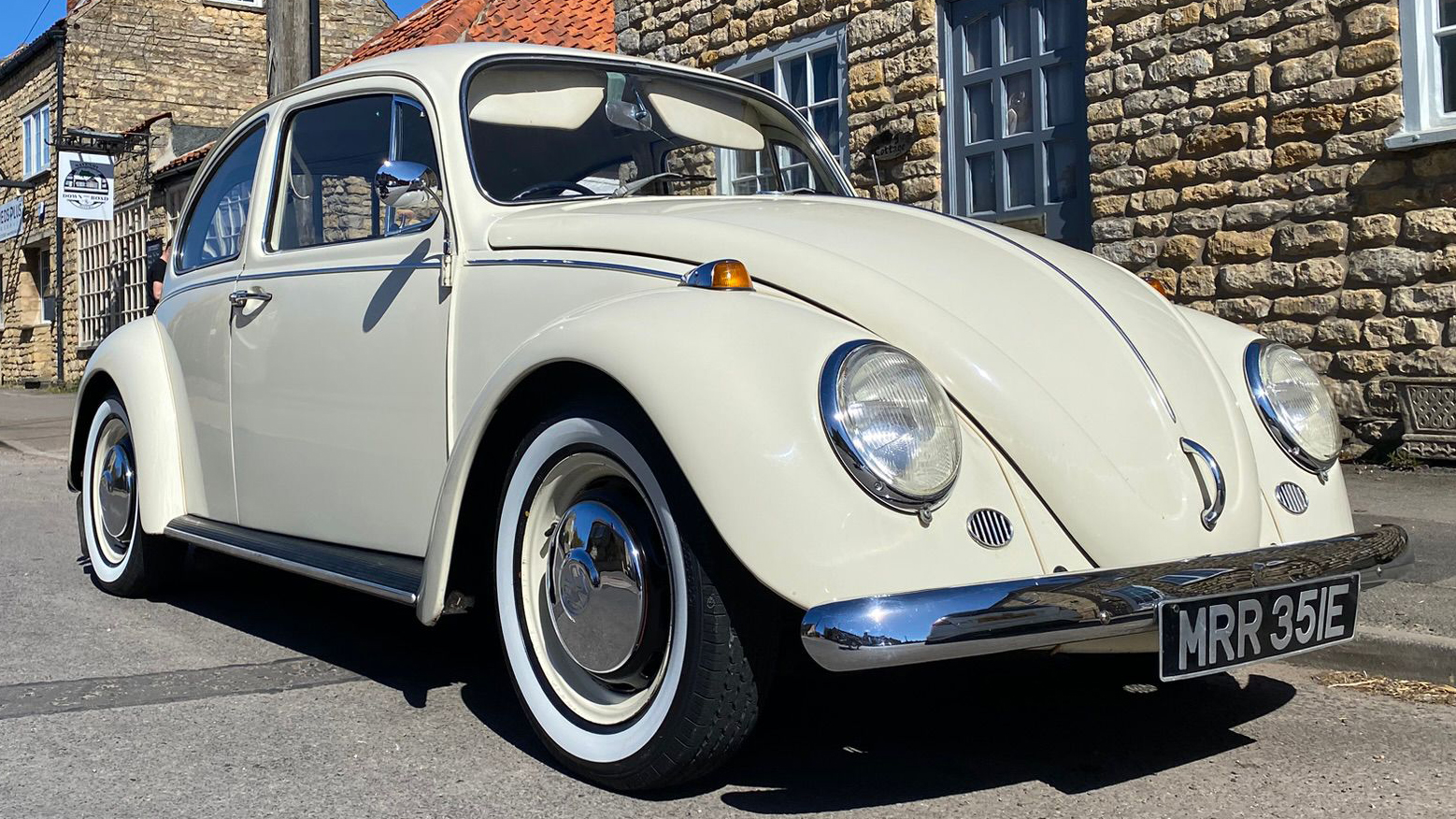 Cream classic Volkswagen Beetle parked outdoors, ideal for wedding car hire with chrome detailing and whitewall tyres