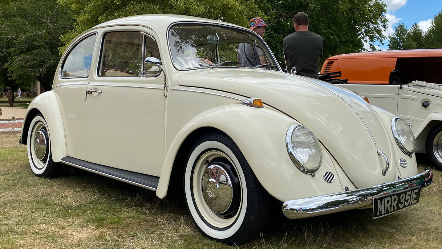 Front right view of a cream classic Volkswagen Beetle wedding car with rounded headlights and chrome bumper
