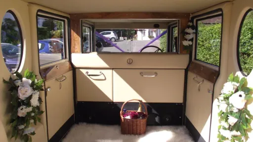 Rear cabin of a 1930s style Imperial wedding car showing cream leather buttoned seating and traditional interior trim.
