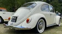 Rear right view of a cream classic Volkswagen Beetle wedding car with chrome detailing and whitewall tyres