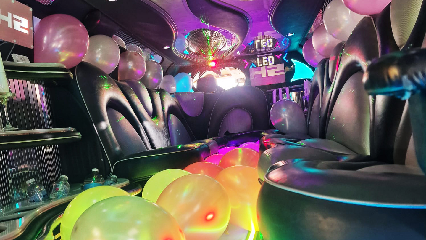 Hummer limousine interior with black leather seating, colour changing LED lights and balloon decorations.