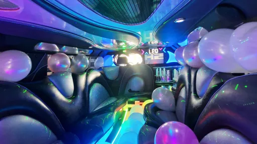 Stretched Hummer limousine interior showing luxury leather seats, fibre optic ceiling and nightclub style lighting.