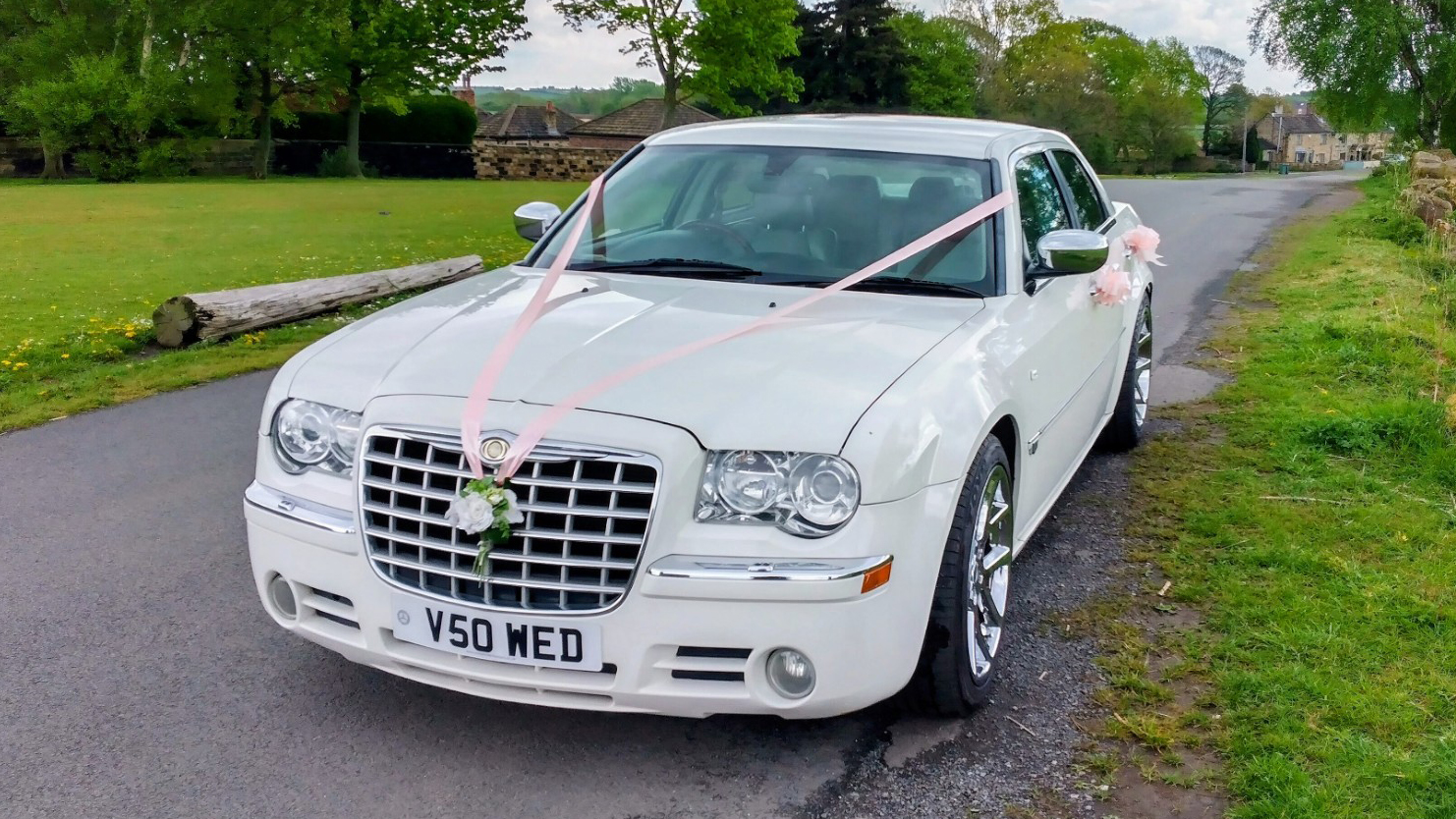 Front view of white Chrysler 300C saloon wedding car with bonnet ribbon and bow