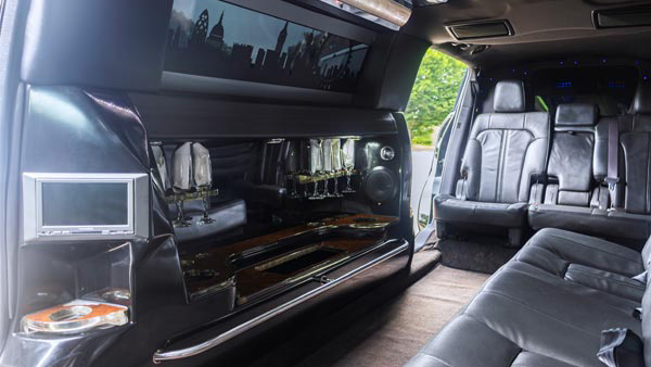 Interior of black Lincoln MKT stretch limousine featuring leather seating, LED lighting, bar area and TV screen.