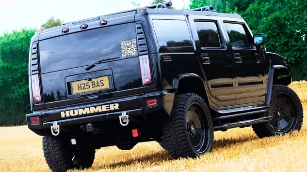 Rear three quarter view of black Hummer H2 showing spare wheel, raised suspension and tinted windows.
